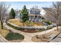 Charming blue two-story home featuring a well-maintained front yard and a classic white picket fence at 301 Indian Peaks W Trl, Lafayette, CO 80026