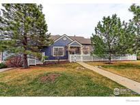 Charming blue home with a well-manicured lawn, complemented by mature trees and a classic white picket fence at 3076 W 112Th Ct # F, Westminster, CO 80031
