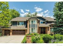 Inviting two-story home featuring a brick and blue exterior, complemented by a well-manicured lawn and a three-car garage at 567 Manorwood Ln, Louisville, CO 80027