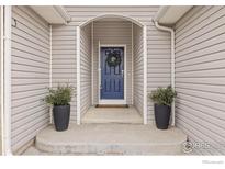 Charming front entrance with a blue door and decorative wreath, potted plants, and covered porch at 629 Mcclure Ave, Firestone, CO 80520