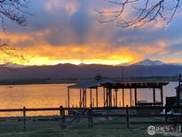 Breathtaking lake view featuring a dock and a vibrant sunset over the mountains at 7975 Anchor Dr, Longmont, CO 80504
