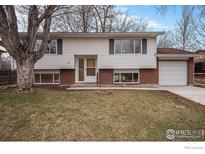 Split-level home features white siding, brick accents, an attached garage, and a well-maintained front yard at 9 James Cir, Longmont, CO 80501
