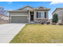 Charming single-story home featuring stone accents, an attached garage, and a well-manicured front yard at 11180 Carbondale St, Firestone, CO 80504