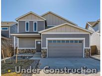 Two-story home featuring stone accents, a two-car garage, neutral color palette, and professional landscaping at 786 Griffith St, Lochbuie, CO 80603