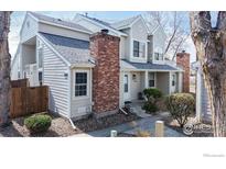 Inviting exterior view of a two-story townhome with a well-maintained yard and a classic brick chimney at 8300 W 87Th Dr # B, Arvada, CO 80005