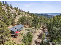 Beautiful home nestled in a mountain landscape with a deck and an outdoor seating area at 94 Spring Ln, Boulder, CO 80302
