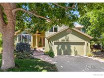 Charming home with a two-car garage, green siding, mature landscaping, and a welcoming walkway to the front entrance at 1117 Barberry Ct, Boulder, CO 80305