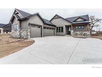 Craftsman home showcasing a spacious driveway, two-car garage, and stone detailing at 1288 Eliza Ave, Berthoud, CO 80513