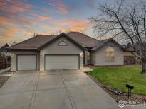 Charming single-story home featuring a three-car garage, tile roof, and well-maintained landscaping at sunset at 1730 Crestone Dr, Longmont, CO 80504