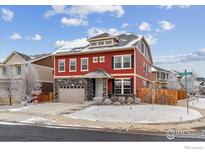 Charming two-story home with a red exterior, stone accents, and a two-car garage, set in a snowy landscape at 23593 E Chenango Pl, Aurora, CO 80016