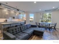 Open-concept living space featuring modern decor, a kitchen island, and a dining area with natural light at 2850 E College Ave # 105, Boulder, CO 80303