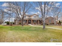 Charming two-story brick home featuring mature trees, a well-manicured lawn, and a welcoming entrance at 3806 Singletree Ct, Mead, CO 80542