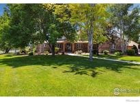 Beautiful home featuring mature trees, lush green lawn, and a welcoming brick exterior at 3806 Singletree Ct, Mead, CO 80542