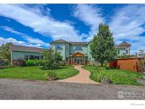 Charming two-story home with lush lawn, mature trees, and inviting walkway to covered front porch at 4514 Hoot Owl Dr, Berthoud, CO 80513