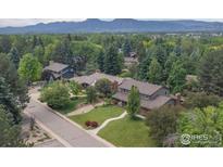 Stunning aerial view of a home surrounded by lush greenery and the Rocky Mountains in the background at 6916 Hunter Pl, Boulder, CO 80301
