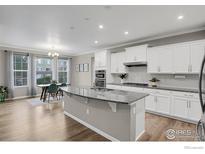 Bright kitchen boasts white cabinets, granite countertops, stainless appliances, and eat-in dining area with backyard views at 9968 E Kansas Ave, Aurora, CO 80247