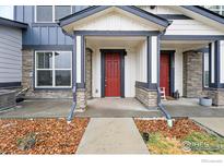 Inviting townhome entrance with a red door, stone accents, and well-maintained landscaping at 111 Ambrose St, Erie, CO 80516