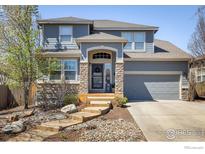 Charming two-story home featuring a stone facade, a two-car garage, and a well-manicured front yard at 2353 Aral Dr, Longmont, CO 80504