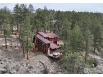 Mountain home nestled among trees featuring a deck, hot tub, and rustic exterior at 286 S Rainbow Trl, Evergreen, CO 80439