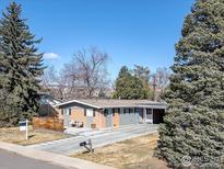 Charming single-story home featuring a brick and gray exterior, mature trees, and a spacious driveway at 4965 Ricara Dr, Boulder, CO 80303