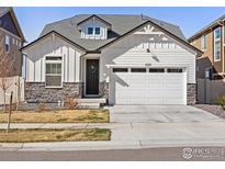 Charming home featuring white siding, stone accents, and a two-car garage, creating a welcoming curb appeal at 1059 Larkspur Dr, Erie, CO 80516