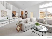 Bright living room featuring a comfortable grey sofa and an open floor plan leading to the kitchen and dining area at 14214 Waterside Ln, Broomfield, CO 80023