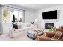 Bright living room featuring a fireplace, modern furniture and lots of natural light at 5861 Mt Shadows Blvd, Firestone, CO 80504