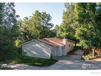 Charming single-story home with a neutral exterior, driveway and mature trees creating a private setting at 6396 Twin Lakes Rd, Boulder, CO 80301