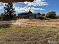 Two-story home with a chimney and an attached garage situated on a grassy lot under a partly cloudy sky at 937 Glenview Dr, Berthoud, CO 80513