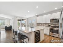 Bright, modern kitchen features an island with seating, stainless steel appliances, and light countertops at 1458 Lander Ln, Lafayette, CO 80026