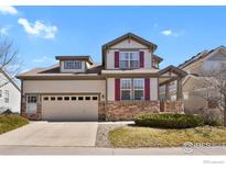 Charming two-story home with a stone accent, neutral siding, red shutters, and a well-manicured lawn at 1533 Bellflower Dr, Brighton, CO 80601