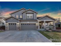 Charming two-story home with a three-car garage and inviting covered porch with stone accents at 1831 Ashford Cir, Longmont, CO 80504