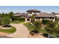 Inviting home featuring stone accents, a curved driveway, and manicured landscaping on a sunny day at 2600 High Prairie Way, Broomfield, CO 80023
