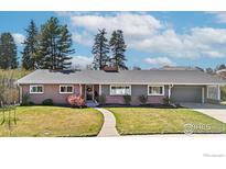 Charming single-story home with brick and gray exterior, manicured lawn and walkway leading to the front door at 545 S Harrison Ln, Denver, CO 80209