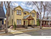 Charming two-story yellow home with landscaped yard and inviting front porch at 832 Neon Forest Cir, Longmont, CO 80504