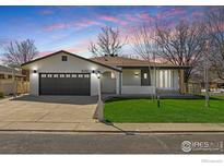 Charming single-story home with a well-manicured lawn, gray garage door, and freshly painted white brick at 1643 Vivian St, Longmont, CO 80501