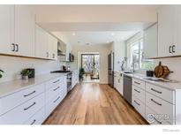 Modern kitchen with white cabinets, stainless steel appliances and hardwood floors at 3786 Eldorado Springs Dr, Boulder, CO 80303