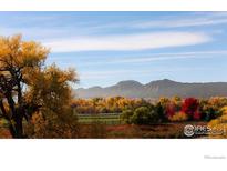 Scenic landscape view featuring fall foliage, a grassy field, and the Rocky Mountains in the background at 5196 Oxford Rd, Longmont, CO 80503