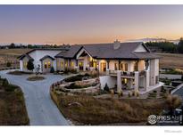 Expansive home featuring stone accents, covered patio, beautiful landscaping, and circular driveway at 6689 Asher Ct, Longmont, CO 80503