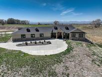 Sprawling single-story home with lush lawn, circular driveway, and mountain views at 7777 Aggregate Blvd, Erie, CO 80516