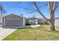 Charming single-story home featuring a well-manicured lawn, a two-car garage, and inviting curb appeal at 1002 Stage Dr, Fort Lupton, CO 80621
