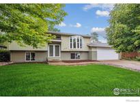 Inviting two-story home featuring a lush green lawn, beautiful bay window, and attached two car garage at 1518 Vivian St, Longmont, CO 80501