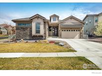 Charming single-Gathering home featuring stone accents, manicured lawn, and attached two-car garage at 16392 Spanish Peak Way, Broomfield, CO 80023