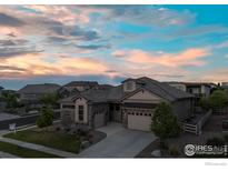 Charming single-story home with a well-manicured lawn and a two-car garage, nestled under a beautiful sunset sky at 16392 Spanish Peak Way, Broomfield, CO 80023