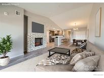 Bright open-concept living room featuring a fireplace and views of the kitchen and dining area at 2435 Calais Dr # A, Longmont, CO 80504