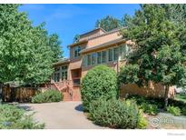 Two story home featuring manicured landscaping, mature trees, and a stained wood entry at 3895 Norwood Ct, Boulder, CO 80304