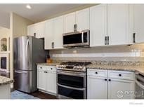 Modern kitchen with white cabinets, stainless steel appliances, and granite countertops at 4215 Bella Vista Dr, Longmont, CO 80503