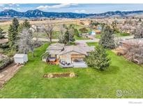 Expansive backyard with green lawn, deck, hot tub, storage shed, and mountain views at 5855 Rustic Knolls Dr, Boulder, CO 80301