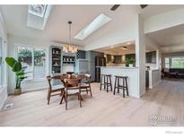 Open concept kitchen with modern light fixtures and a light blue dining nook with a round wooden table at 5855 Rustic Knolls Dr, Boulder, CO 80301