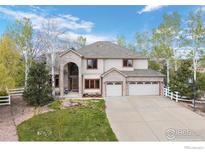 Charming two-story home with a three-car garage, manicured lawn, and mature trees at 7959 Nile Ct, Arvada, CO 80007